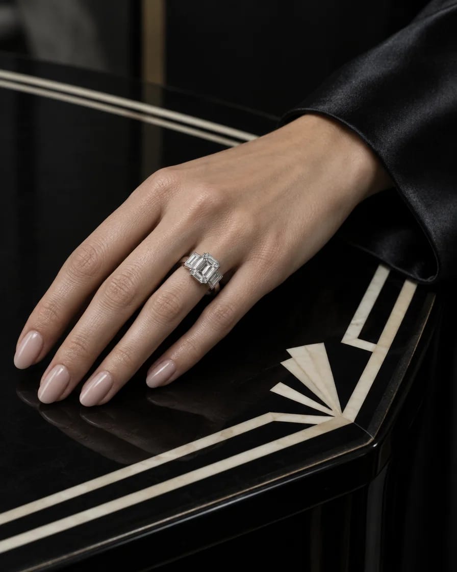 Ruka v čiernom hodvábe s geometrickým diamantovým prsteňom na lakovanom stole